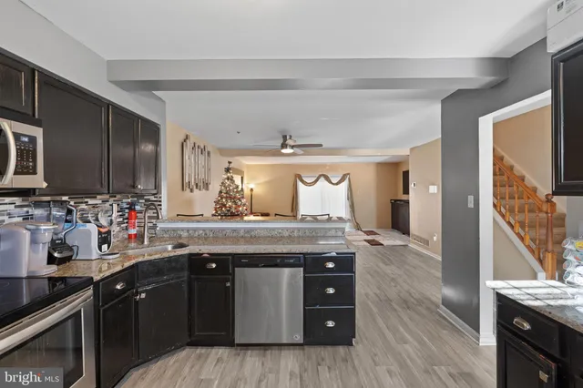a kitchen with granite countertop a sink cabinets and wooden floor