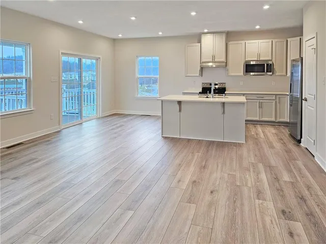 a large kitchen with kitchen island a sink a center island stainless steel appliances and a cabinets