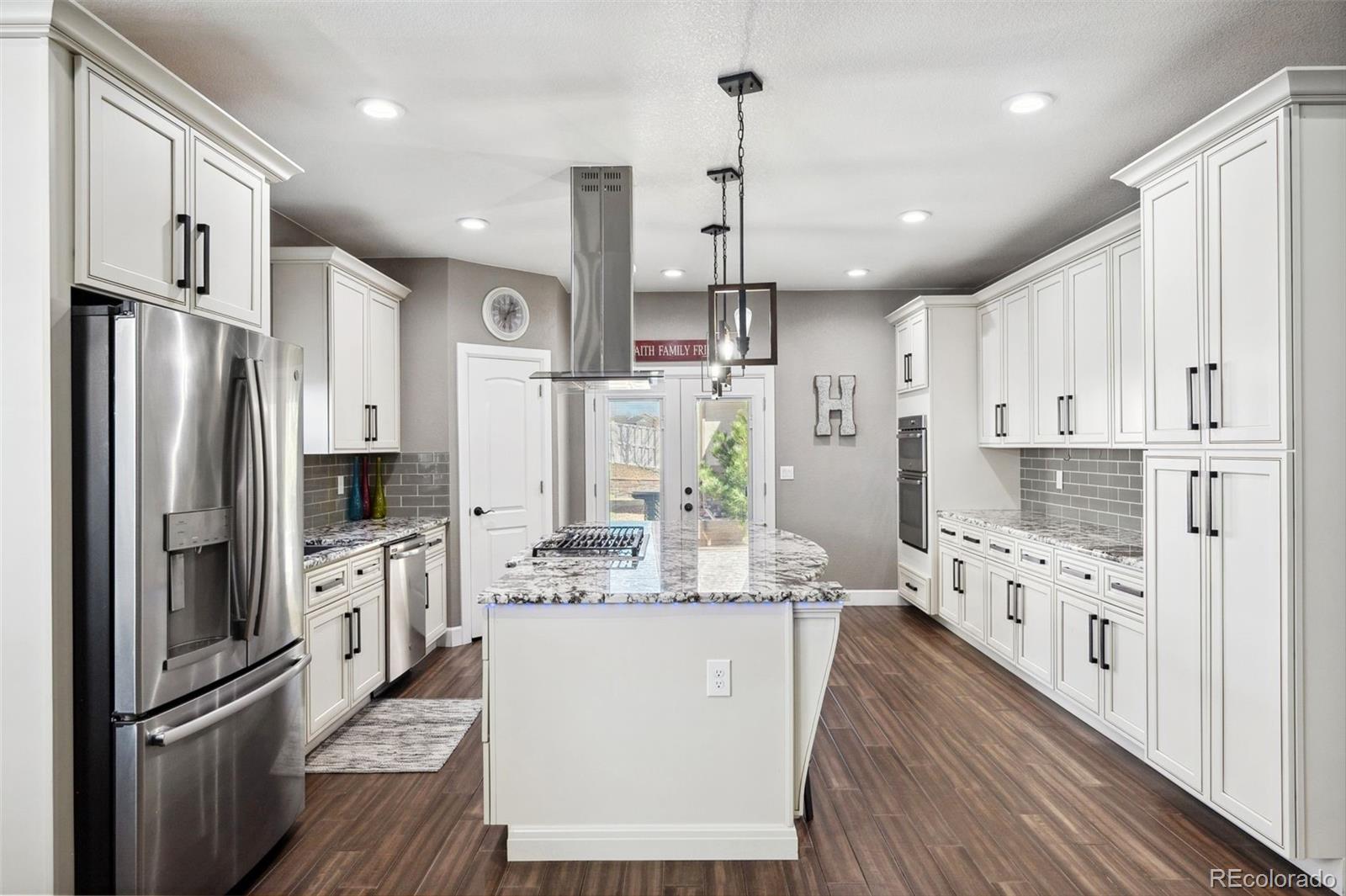 156 Chapel Hill Circle Brighton, CO 80601 - Photo 17 of 48 a large kitchen with stainless steel appliances kitchen island granite countertop a refrigerator a stove a oven and white cabinets with wooden floor