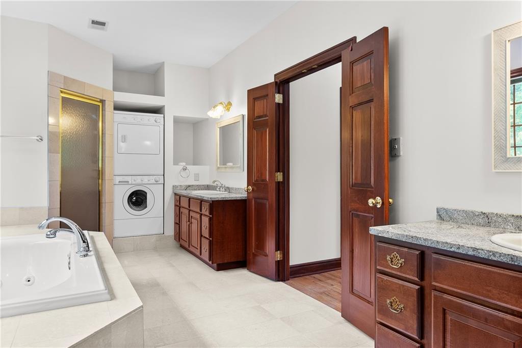 1060 Fox Chapel Road Pittsburgh, PA 15238 - Photo 31 of 50 Ensuite bath with jetted tub, steam shower, dual vanities with granite countertops, and a stackable washer and dryer