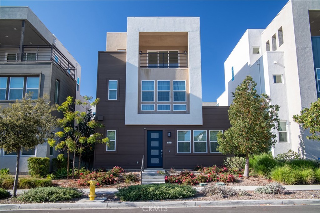 a front view of a multi story residential apartment building with yard and parking
