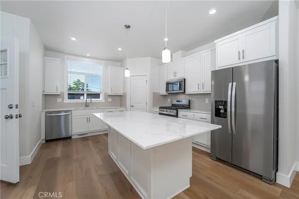 a large kitchen with stainless steel appliances a sink a refrigerator and a stove top oven