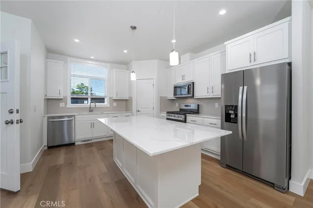 a large kitchen with stainless steel appliances a sink a refrigerator and a stove top oven