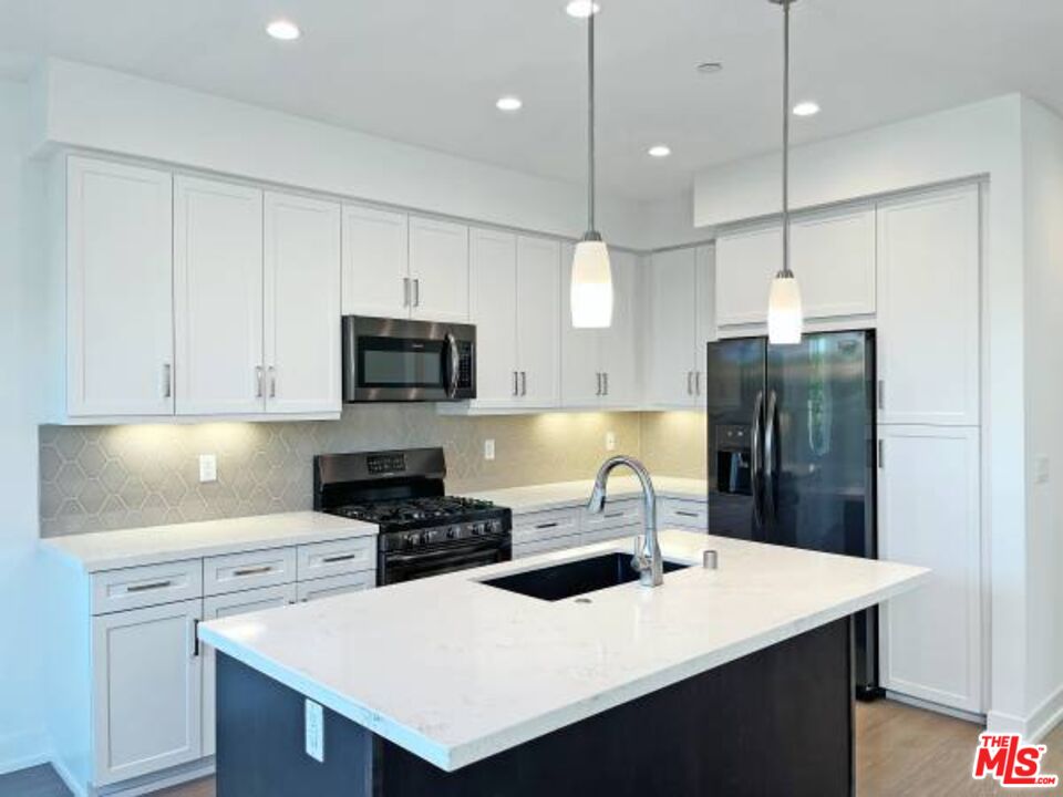 a kitchen with a sink a stove a refrigerator and white cabinets