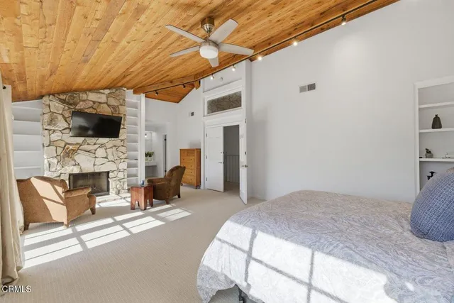 a bedroom with a bed a flat screen tv and fireplace