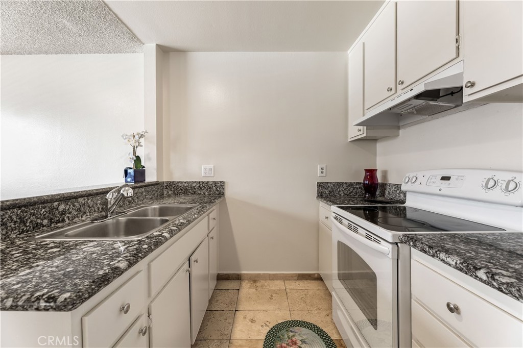 5530 Ackerfield Avenue, Unit 206 Long Beach, CA 90805 - Photo 6 of 33 a kitchen with granite countertop a sink and a stove
