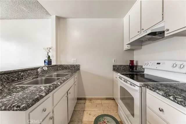 a kitchen with granite countertop a sink and a stove