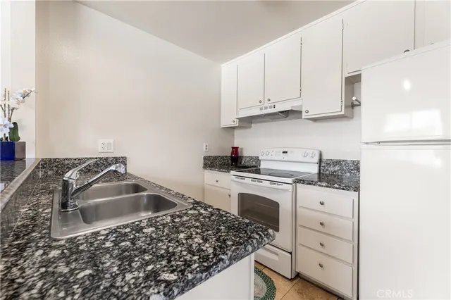 a kitchen with granite countertop a sink stove and cabinets