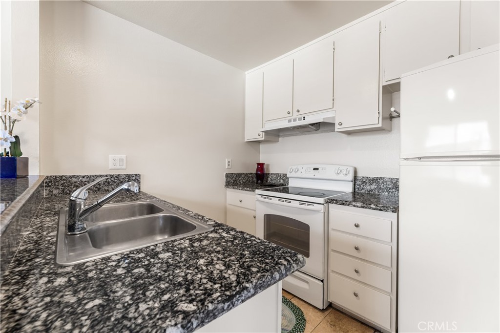 5530 Ackerfield Avenue, Unit 206 Long Beach, CA 90805 - Photo 9 of 33 a kitchen with granite countertop a sink stove and cabinets