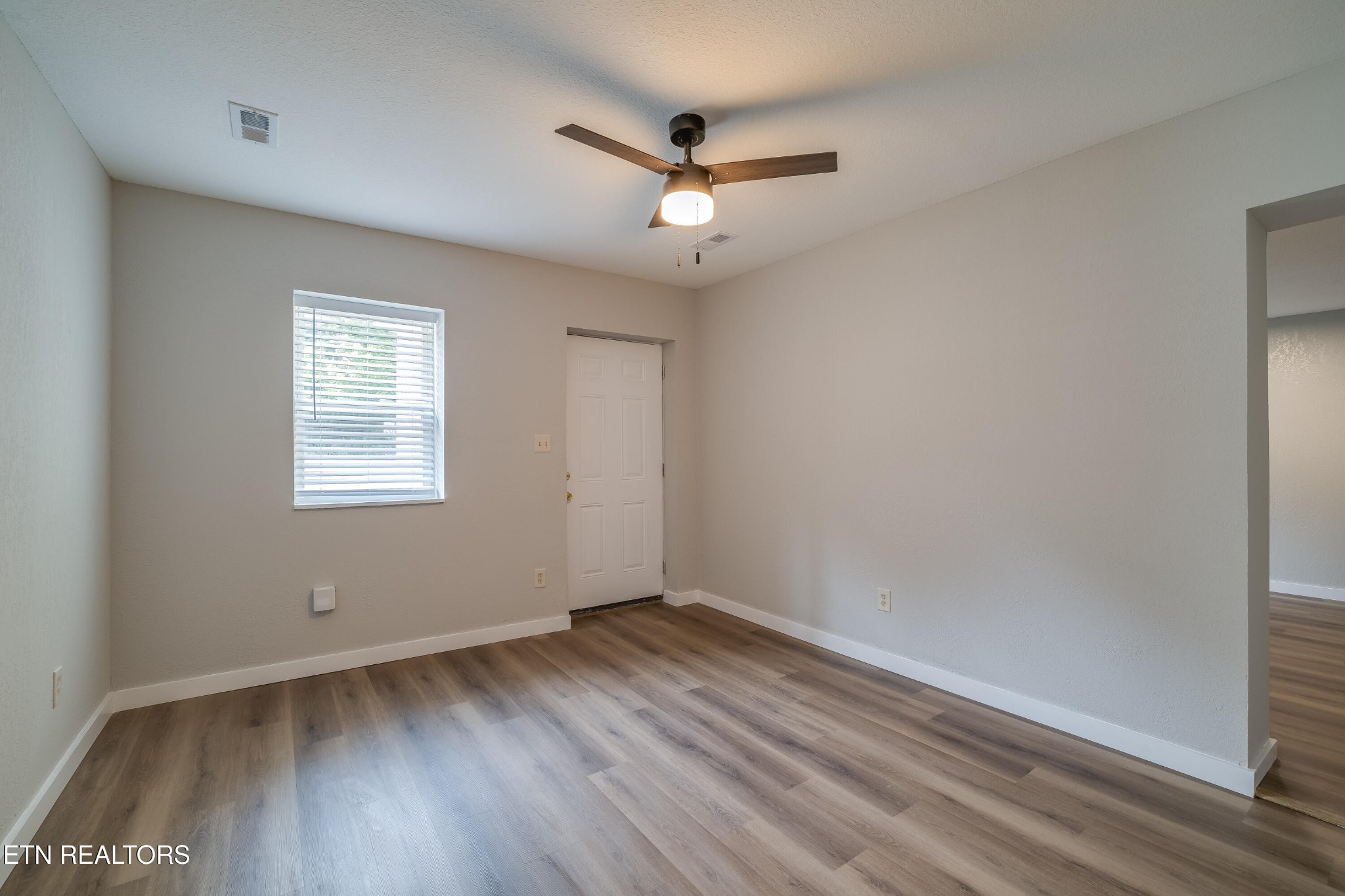 4707 Wildwood Road Maryville, TN 37804 - Photo 3 of 18 an empty room with wooden floor ceiling fan and windows