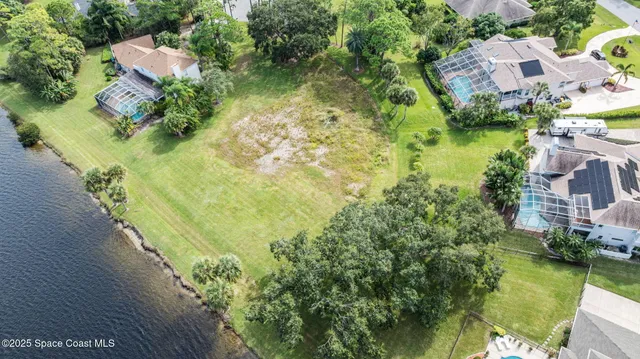 a view of a lake with lawn chairs and large trees