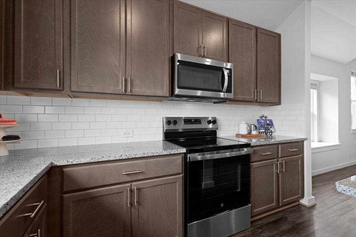 321 Buffalo View Lane Georgetown, TX 78628 - Photo 9 of 29 Granite countertops, white subway tile backsplash, and a stainless oven and a built-in microwave