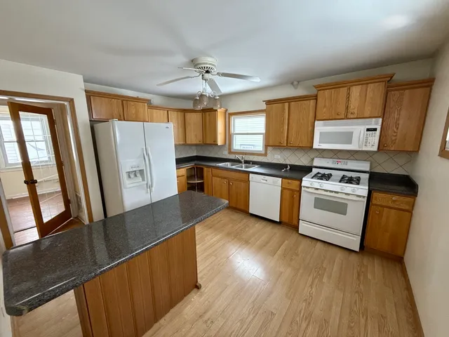 a kitchen with stainless steel appliances granite countertop a stove a sink dishwasher a refrigerator and a stove with wooden floor