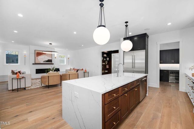 a large kitchen with stainless steel appliances kitchen island a large counter top a stove and a living room view