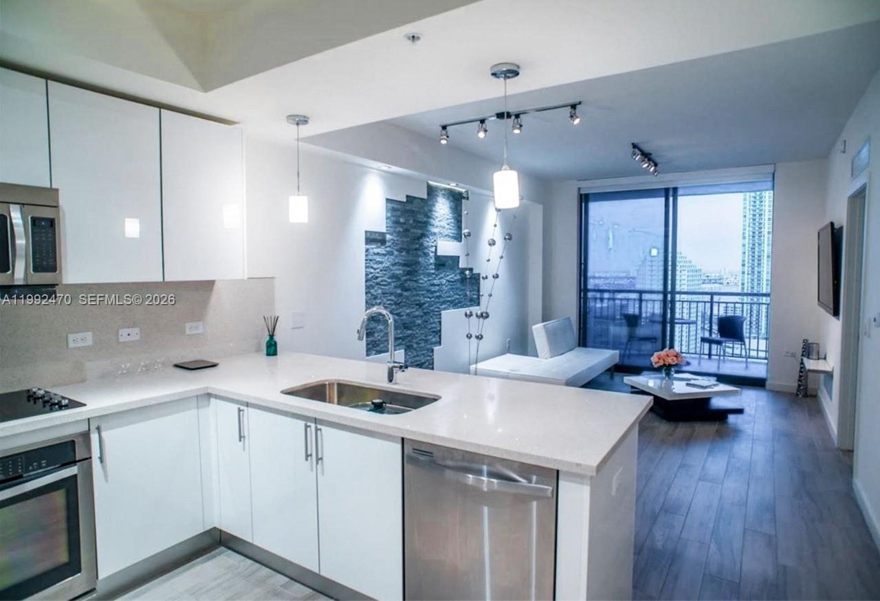 999 Southwest 1st Avenue, Unit 3208 Miami, FL 33130 - Photo 11 of 14 a kitchen that has a sink and a stove with wooden floor