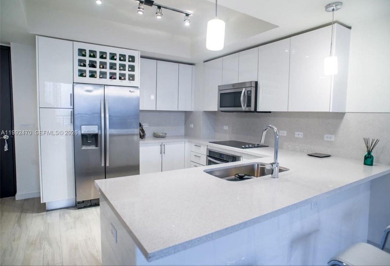 999 Southwest 1st Avenue, Unit 3208 Miami, FL 33130 - Photo 7 of 14 a kitchen with stainless steel appliances a sink a stove a refrigerator and cabinets