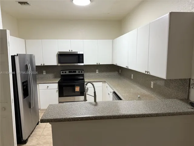 a kitchen with granite countertop a refrigerator and a stove top oven