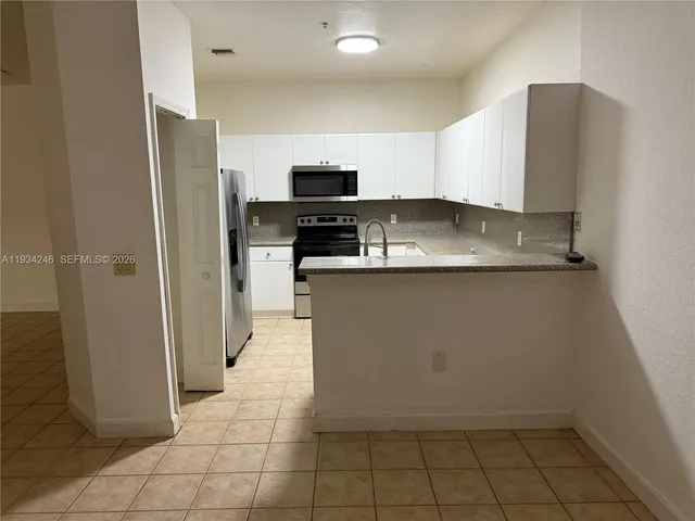 a kitchen with stainless steel appliances a sink a stove a refrigerator a microwave and cabinets