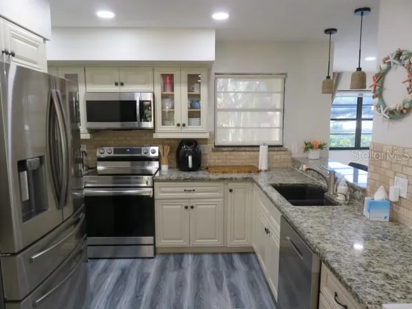 a kitchen with stainless steel appliances granite countertop a sink stove and refrigerator