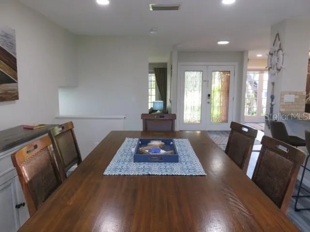 a living room with stainless steel appliances furniture a rug kitchen view and large windows
