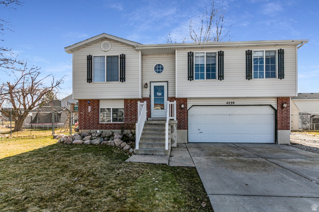 4239 West 5325th Street South Roy, UT 84067 - Photo 1 of 26 Split foyer home with brick siding, driveway, and an attached garage