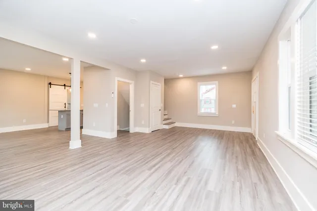 a view of an empty room with wooden floor and window