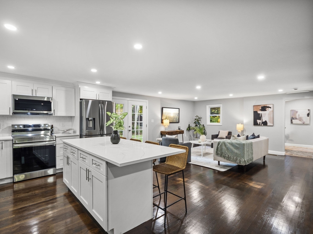 21 Webster Street Andover, MA 01810 - Photo 2 of 24 a large white kitchen with a dining table chairs stove a refrigerator and cabinets