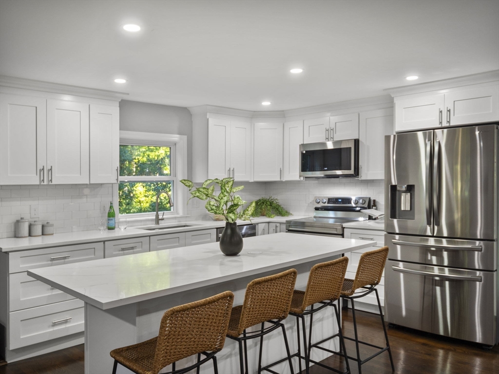 21 Webster Street Andover, MA 01810 - Photo 3 of 24 a kitchen with a table chairs refrigerator and microwave