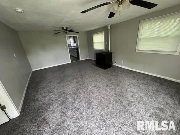 en empty room with windows and ceiling fan