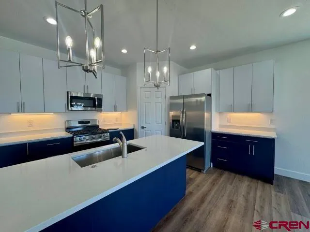 a kitchen with stainless steel appliances a sink a stove a refrigerator and cabinets