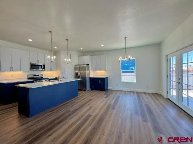 a large kitchen with stainless steel appliances granite countertop a large counter top a stove and a wooden floors