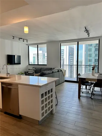 a large kitchen with stainless steel appliances a stove a sink dishwasher a dining table and chairs with wooden floor