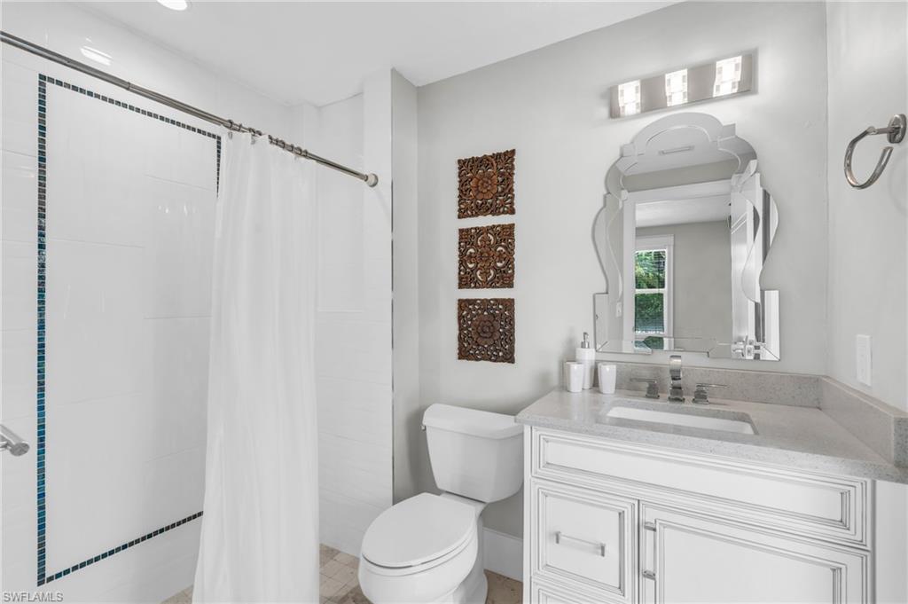 5000 West Boulevard Naples, FL 34103 - Photo 22 of 25 a bathroom with a toilet a sink and a mirror