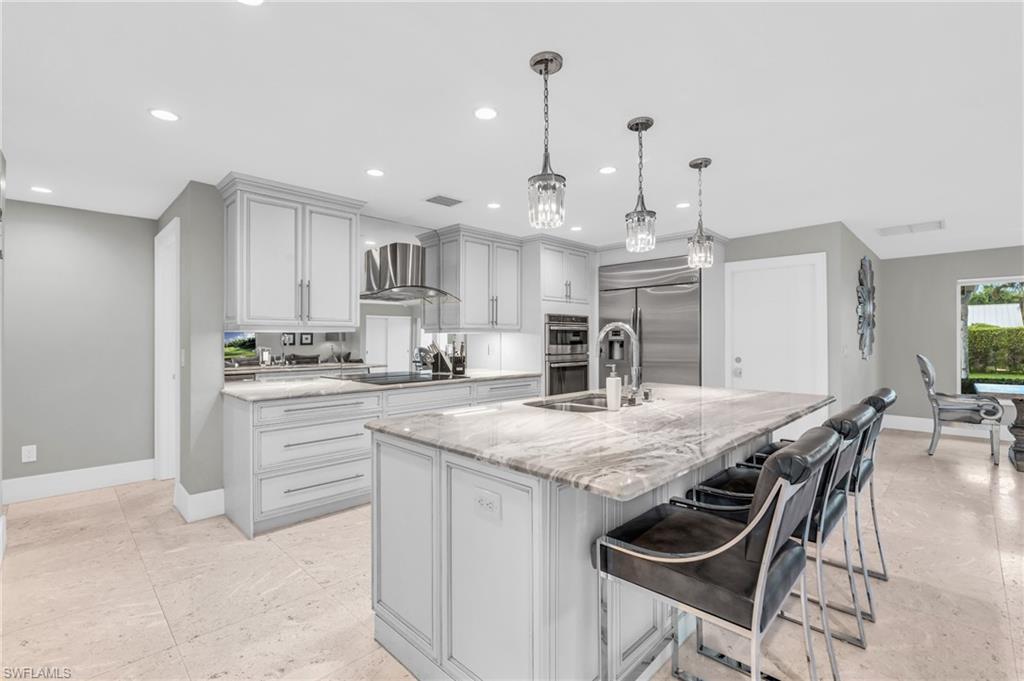 5000 West Boulevard Naples, FL 34103 - Photo 7 of 25 a kitchen with kitchen island a stove a table and chairs in it