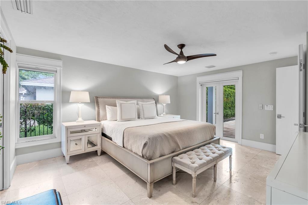 5000 West Boulevard Naples, FL 34103 - Photo 10 of 25 a bedroom with a large bed a chandelier and a large window