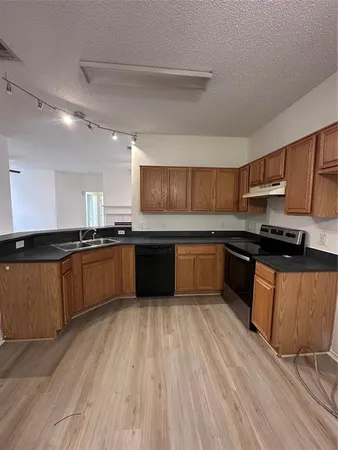 a large kitchen with wooden floors stainless steel appliances a sink and cabinets