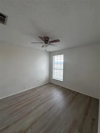 an empty room with wooden floor fan and windows