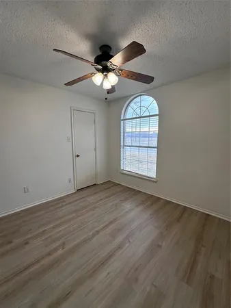 an empty room with wooden floor chandelier and windows