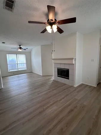 a view of empty room with wooden floor fan and window