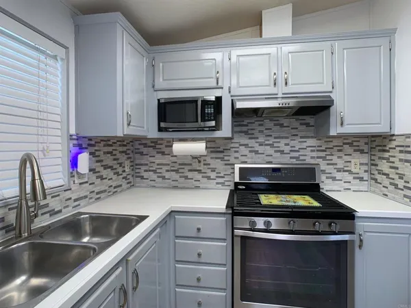 a kitchen with granite countertop white cabinets and stainless steel appliances