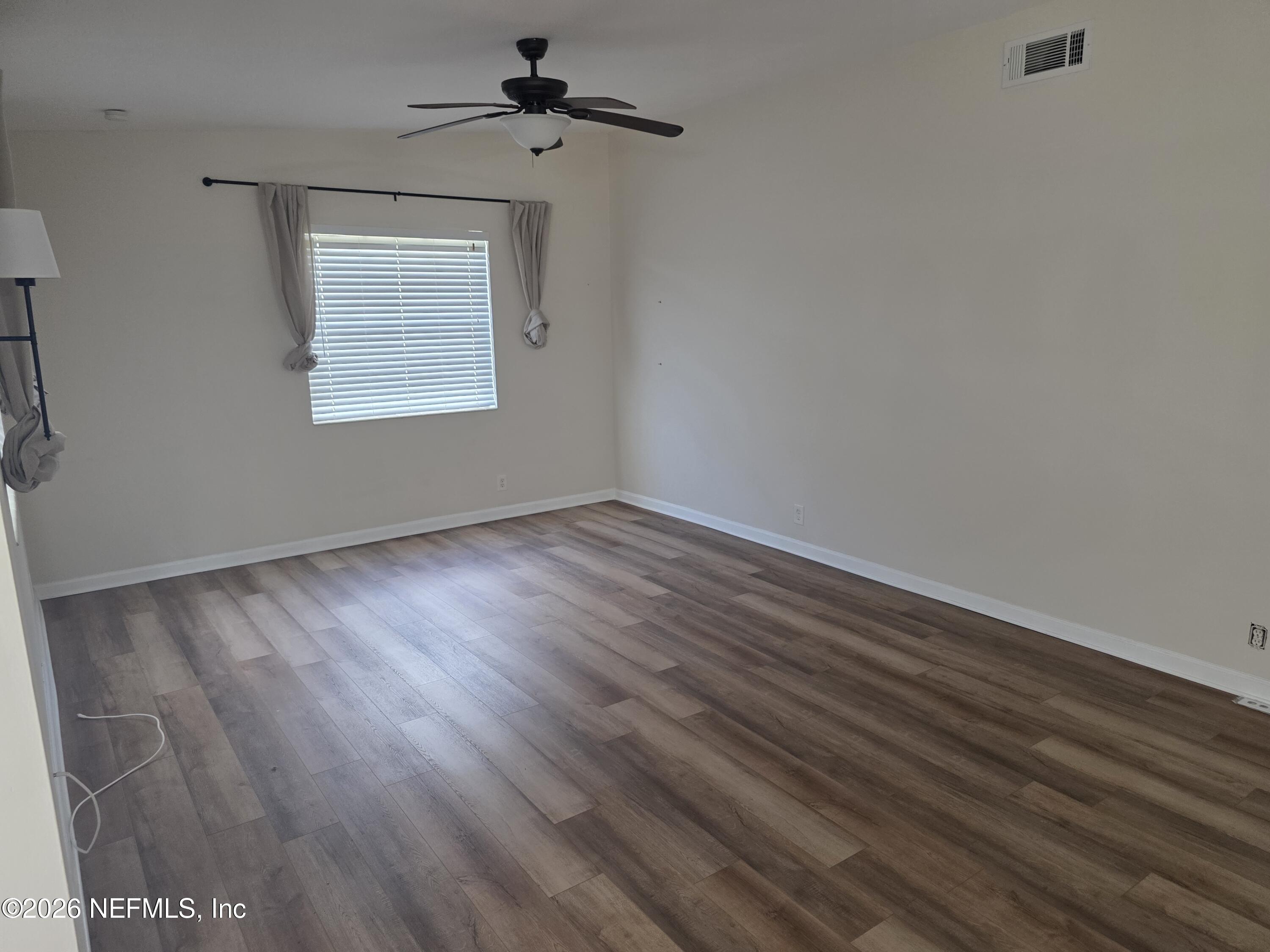 3616 Toledo Road Jacksonville, FL 32217 - Photo 10 of 34 a view of an empty room with wooden floor and a window