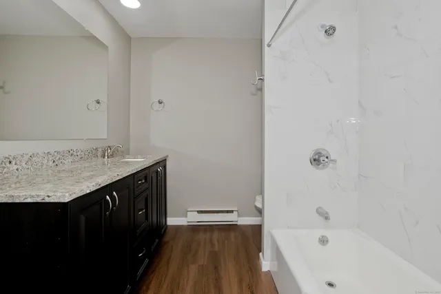 a bathroom with a granite countertop sink a toilet and shower