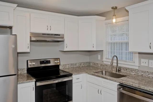 a kitchen with granite countertop a sink dishwasher stove and cabinets