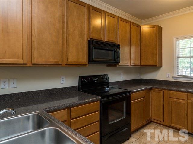 4528 Mistiflower Drive Raleigh, NC 27606 - Photo 8 of 25 a kitchen with granite countertop wood cabinets stainless steel appliances and a window