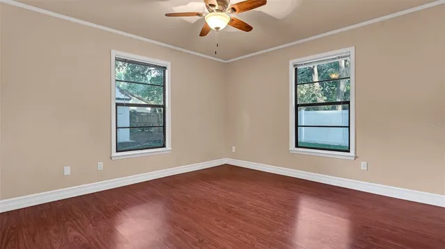 a view of an empty room with wooden floor and a window