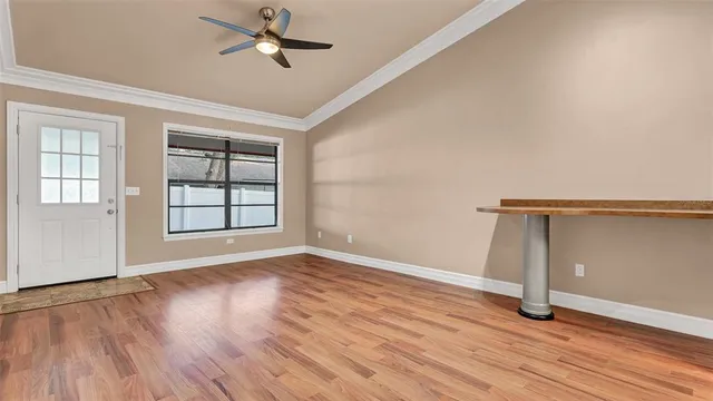 an empty room with wooden floor ceiling fan and windows