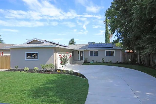 a view of a yard in front of a house with large tree