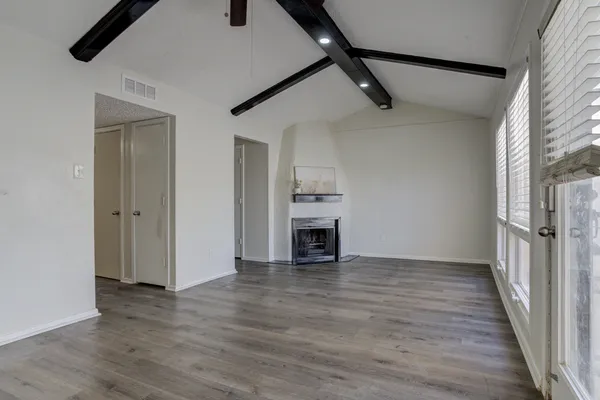 an empty room with wooden floor fireplace and windows