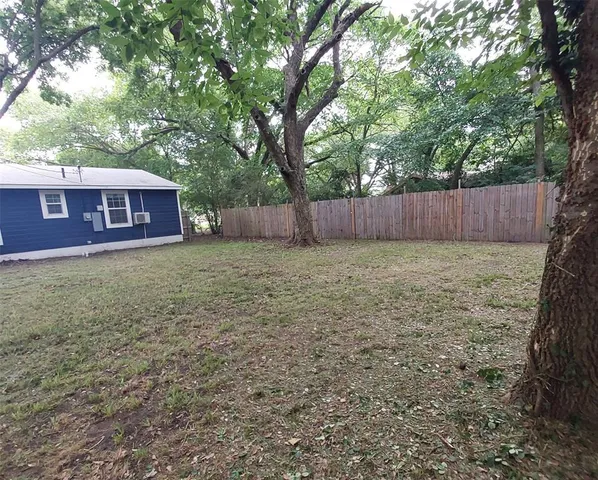 a view of a yard in front of a house with large trees