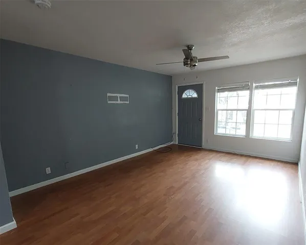 an empty room with wooden floor chandelier and windows
